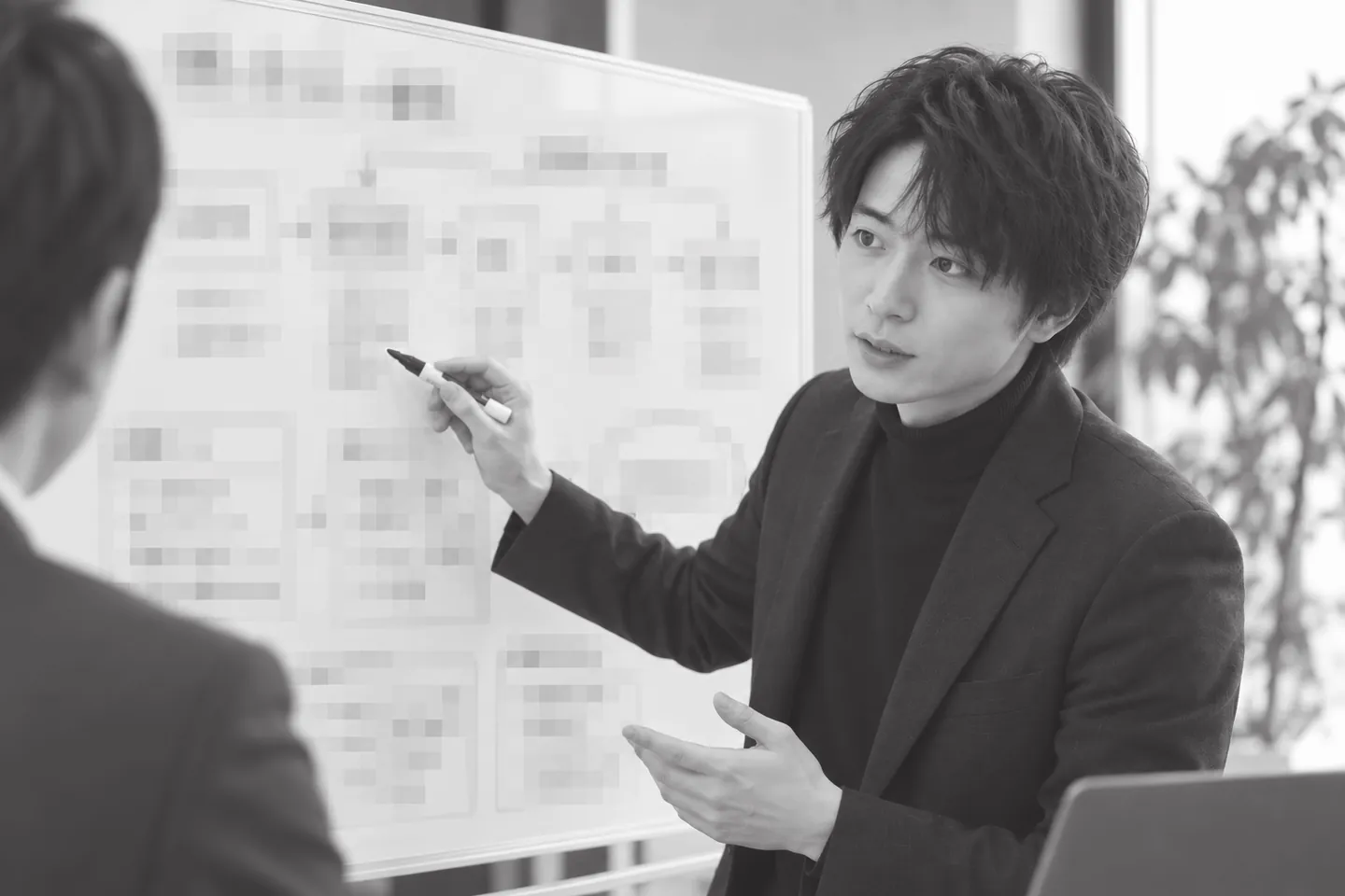 クライアント先で、社員の方とホワイトボードに工程を描きながら業務の棚卸しをしている実際の様子